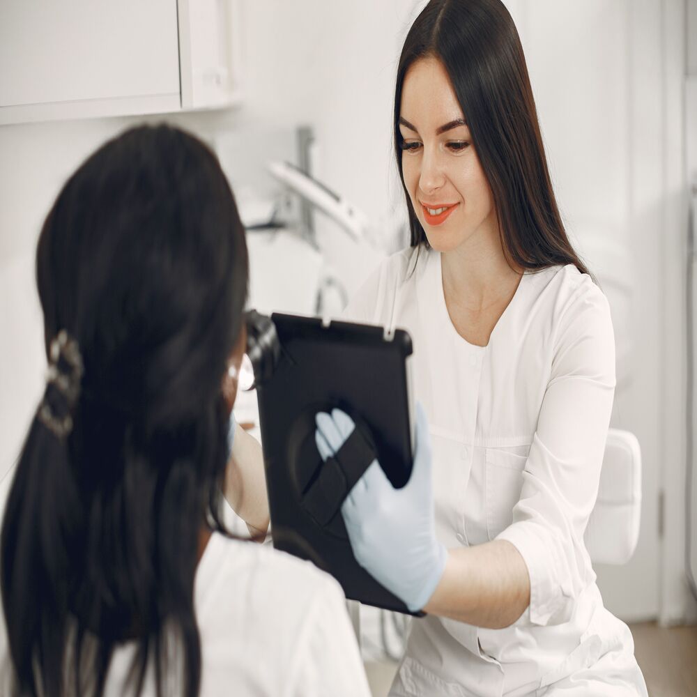 Kỹ thuật viên thẩm mỹ viện xem hồ sơ khách hàng trên máy tính bảng trước khi thực hiện liệu trình